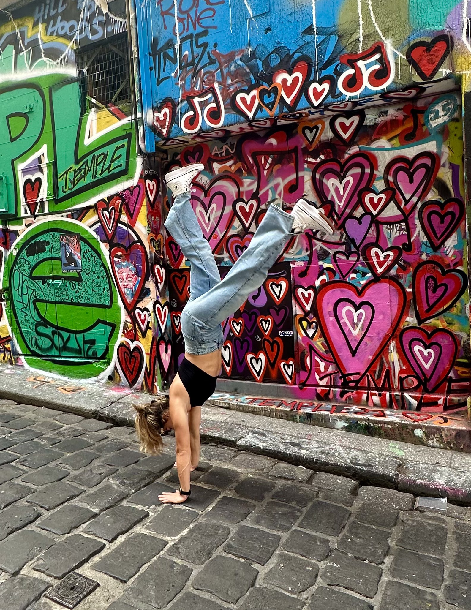 Rach doing a handstand against a graffiti wall